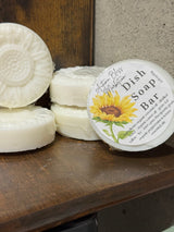 White dish soap bars with a sunflower label on a wooden surface