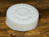 White circular dish soap bar on a wooden surface