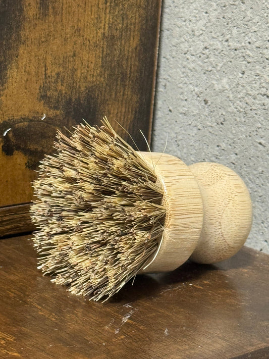 Wooden dish brush with bristle head on a textured surface