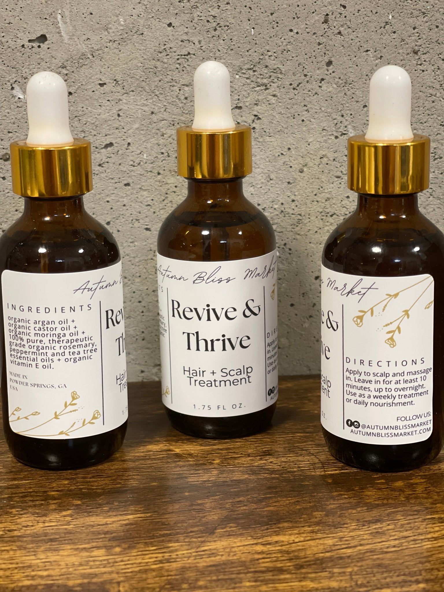 Bottles of 'Revive & Thrive' hair and scalp treatment on a wooden surface.