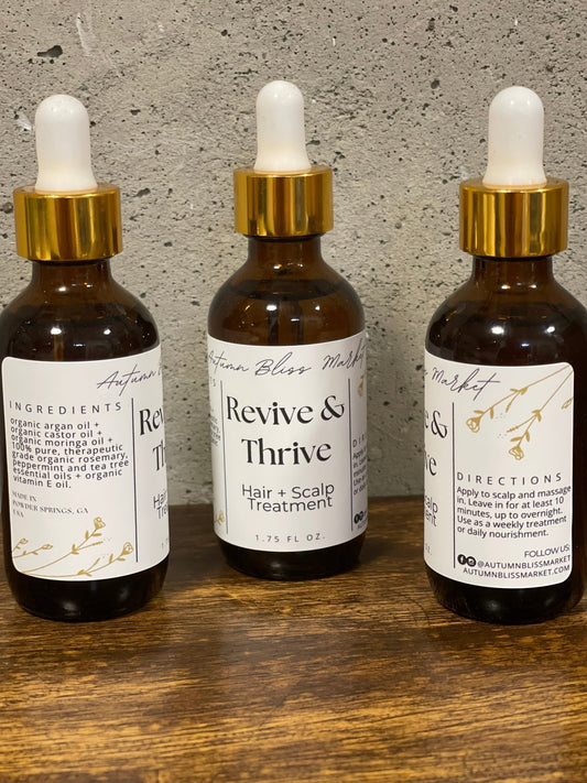 Bottles of 'Revive & Thrive' hair and scalp treatment on a wooden surface.